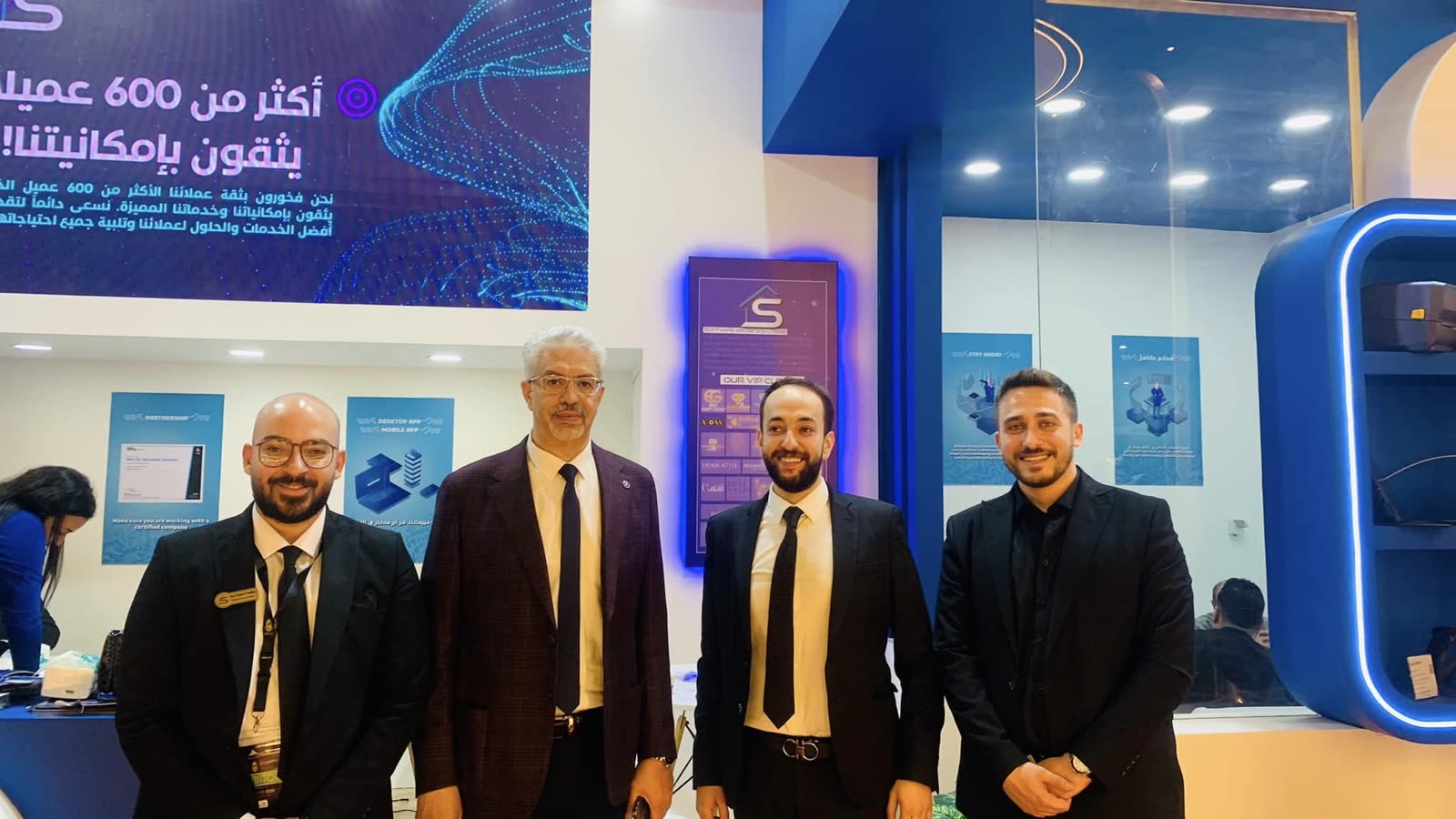 Four members of the SWH team in front of the stand's display wall at NEBU Expo 2023.